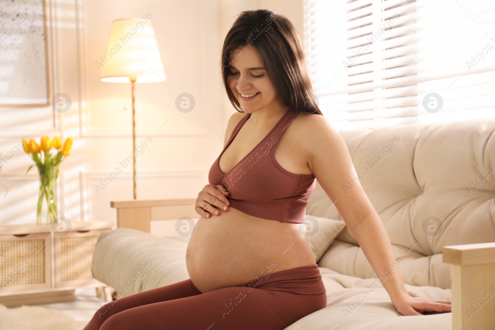 Photo of Pregnant young woman touching belly at home