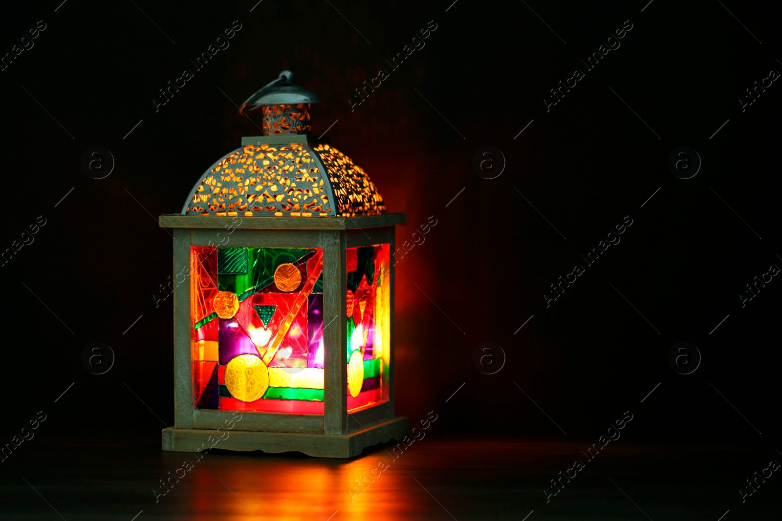 Photo of Decorative Arabic lantern on table against dark background. Space for text