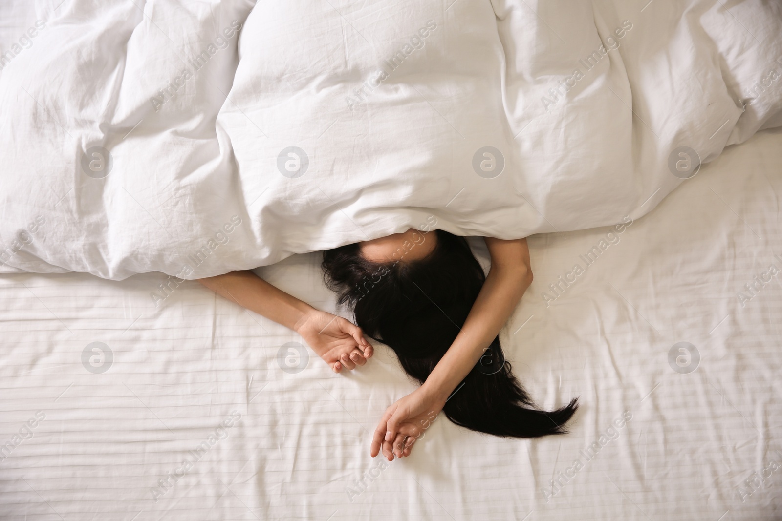 Photo of Young woman sleeping in bed covered with white blanket, top view