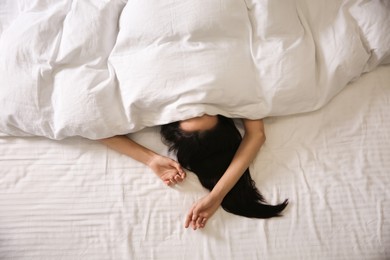 Young woman sleeping in bed covered with white blanket, top view