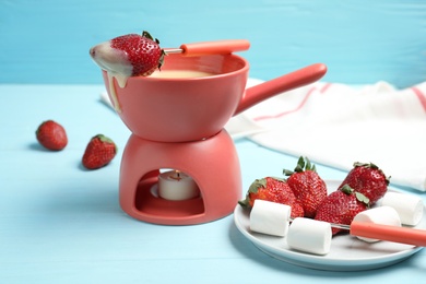 Chocolate fondue with strawberries and marshmallow on wooden table