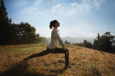 Photo of Woman practicing yoga in mountains at sunrise