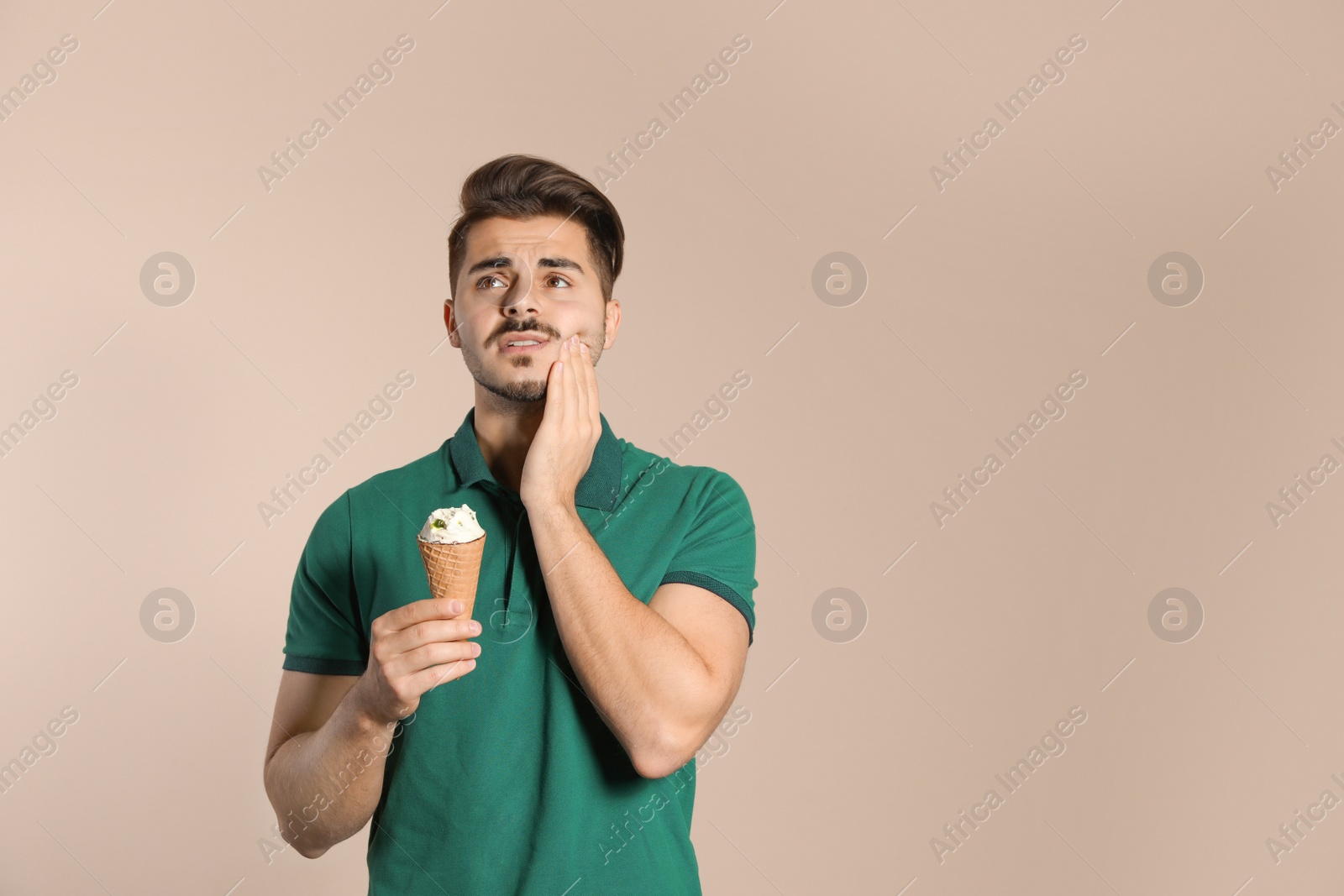 Photo of Emotional young man with sensitive teeth and ice cream on color background. Space for text