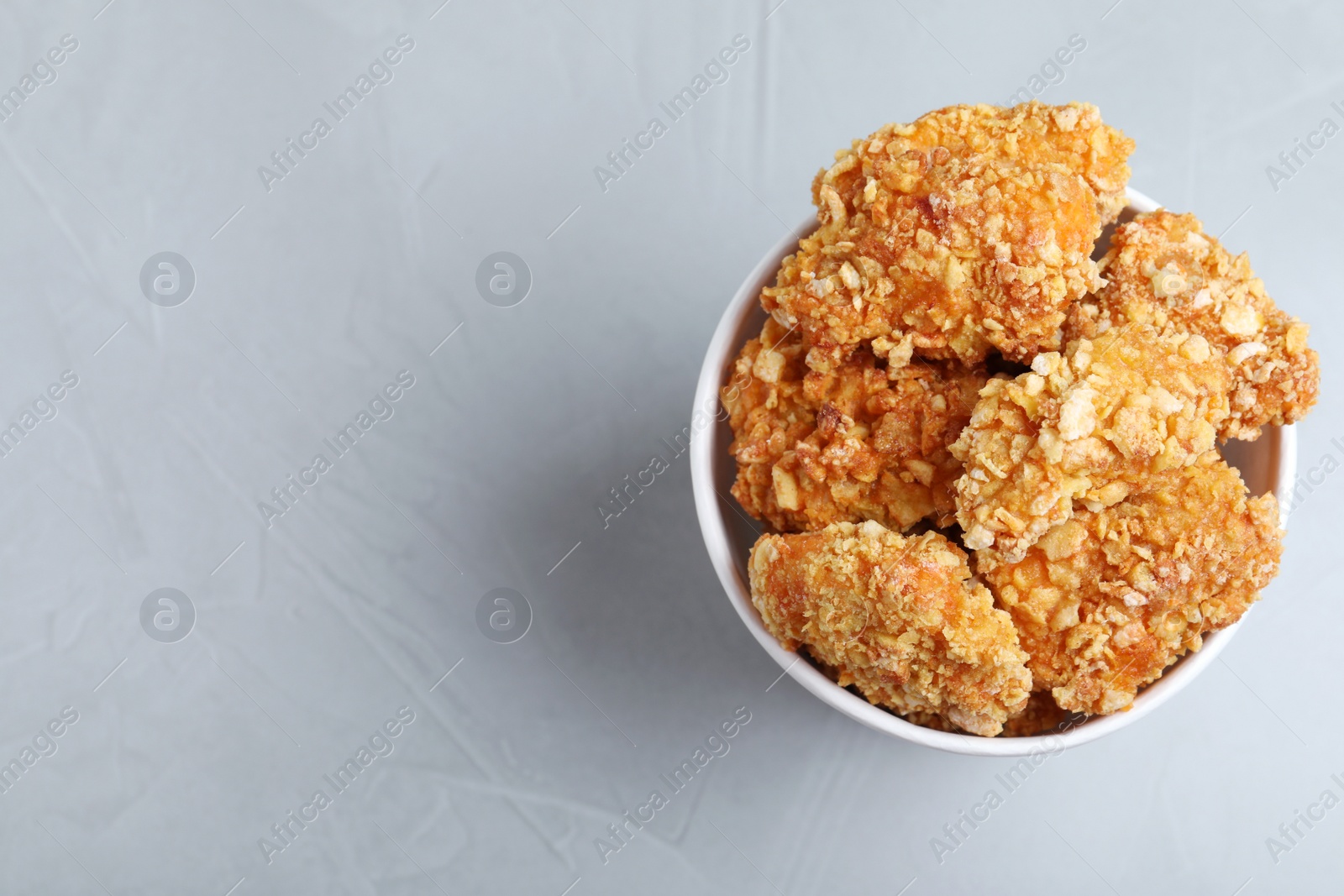 Photo of Bucket with yummy nuggets on light background, top view. Space for text