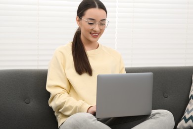 Photo of Woman using laptop on couch at home