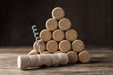 Photo of Corkscrew and wine corks on wooden table