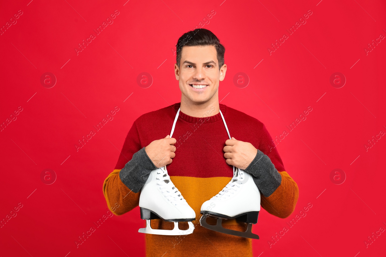 Photo of Happy man with ice skates on red background