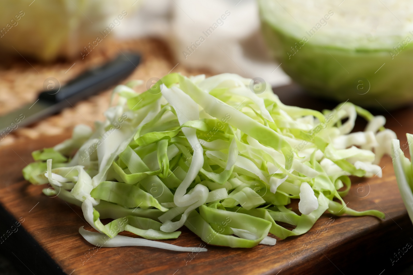 Photo of Fresh shredded cabbage on wooden board, closeup