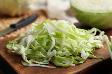 Photo of Fresh shredded cabbage on wooden board, closeup