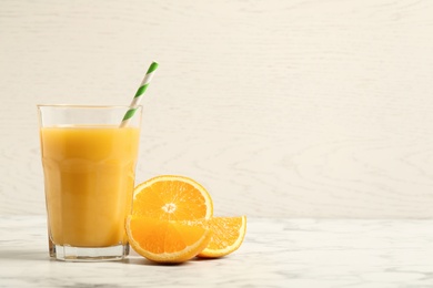 Photo of Glass of orange juice and fresh fruits on white marble table. Space for text