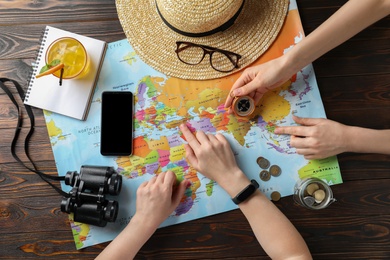 Photo of People with world map and accessories at table, top view. Travel during summer vacation