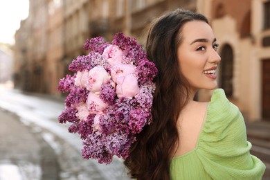 Beautiful woman with bouquet of spring flowers on city street