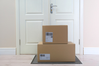 Cardboard boxes on rug near door. Parcel delivery service