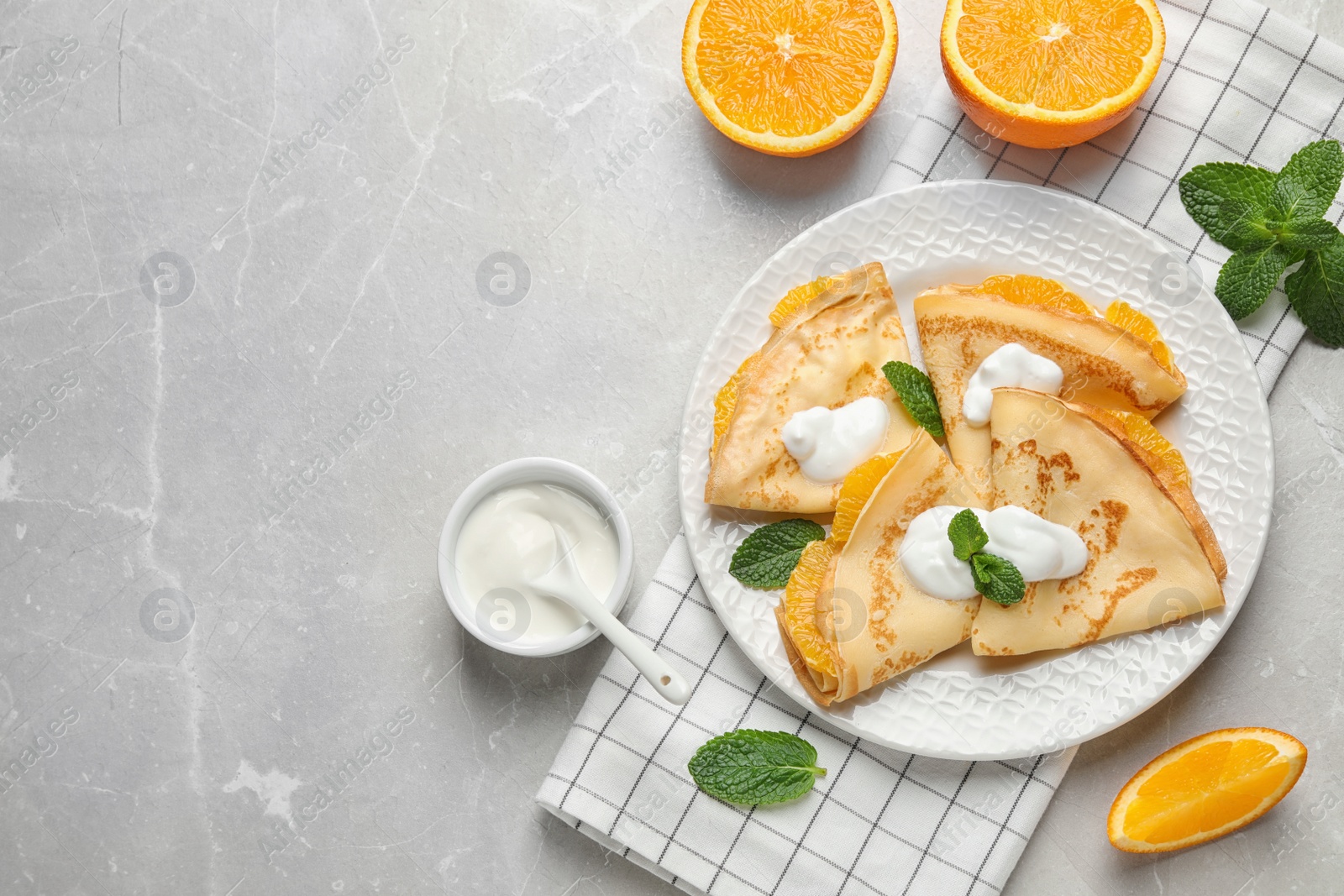 Photo of Delicious thin pancakes with oranges and cream on marble table, flat lay. Space for text