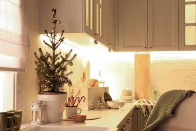 Photo of Small Christmas tree and festive decor on countertop in kitchen