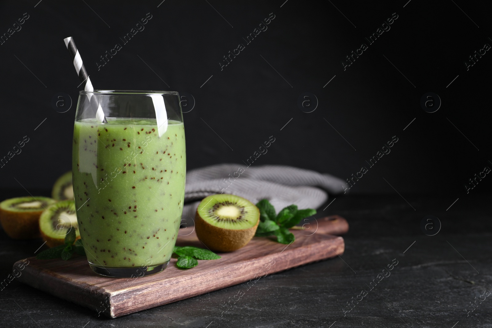 Photo of Delicious kiwi smoothie and fresh ingredients on black table, space for text