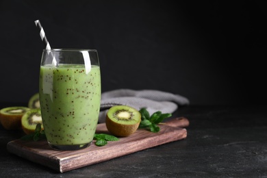 Photo of Delicious kiwi smoothie and fresh ingredients on black table, space for text