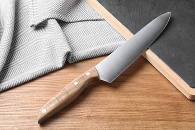 Composition with sharp chef's knife and board on wooden background