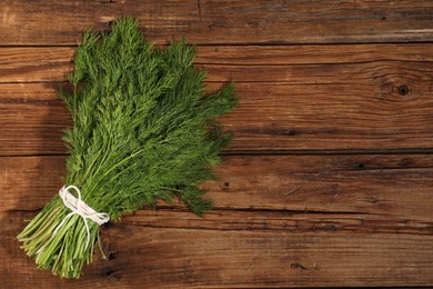 Photo of Bunch of fresh green dill on wooden table, top view. Space for text