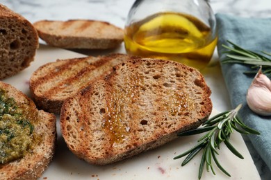 Photo of Tasty bruschettas with oil, rosemary and garlic on board, closeup