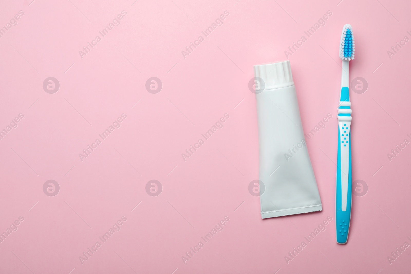 Photo of Blank tube of toothpaste and brush on color background, top view with space for text