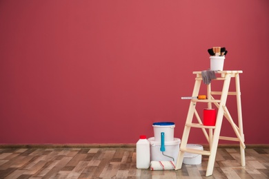 Photo of Step ladder and decorator's tools near color wall