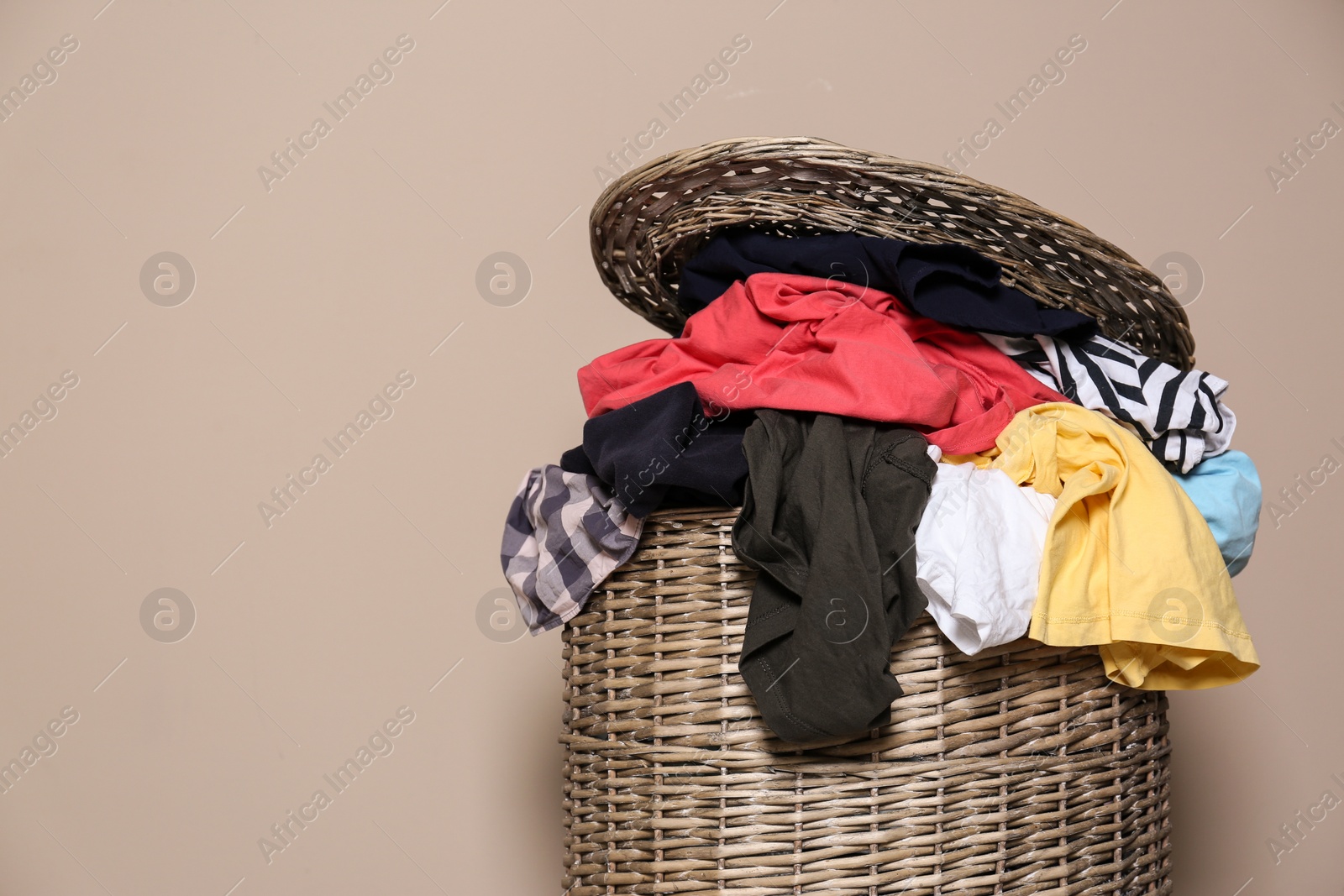 Photo of Laundry basket with dirty clothes on color background. Space for text