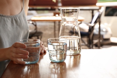 Photo of Woman with glass of water at table indoors