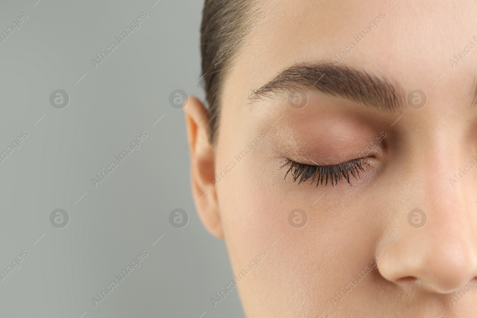 Photo of Young woman with perfect eyebrows on grey background, closeup. Space for text
