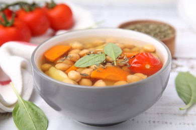 Photo of Tasty chickpea soup in bowl and spices on white wooden table, closeup