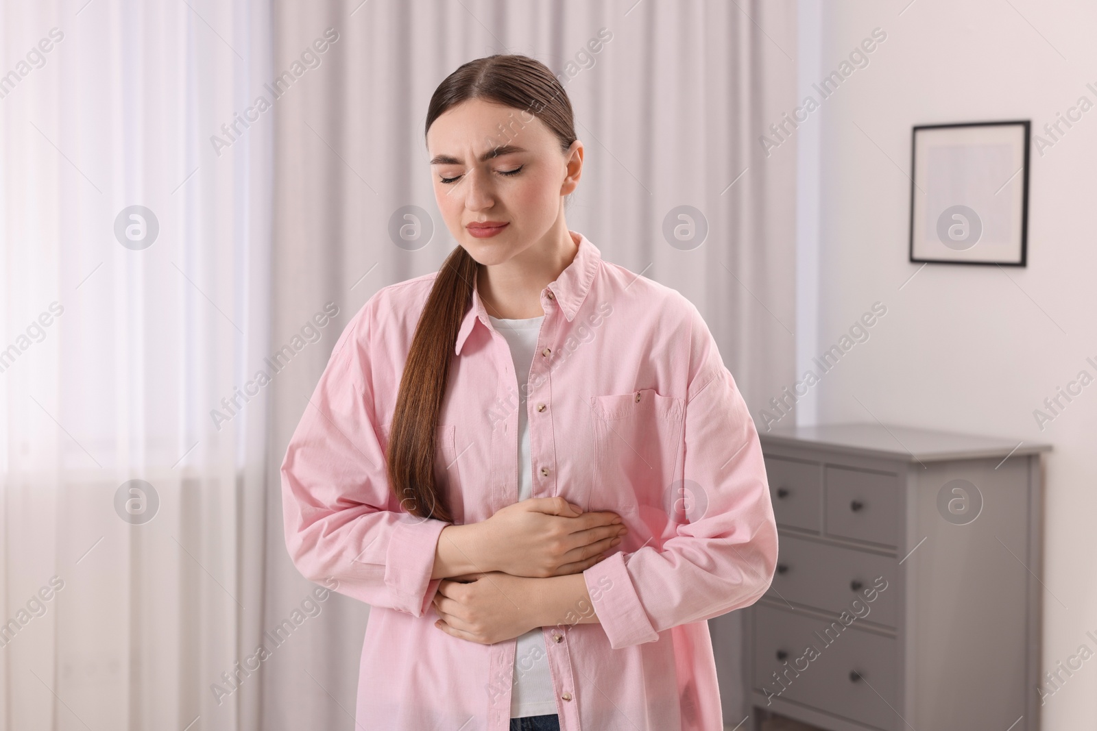 Photo of Young woman suffering from stomach pain at home