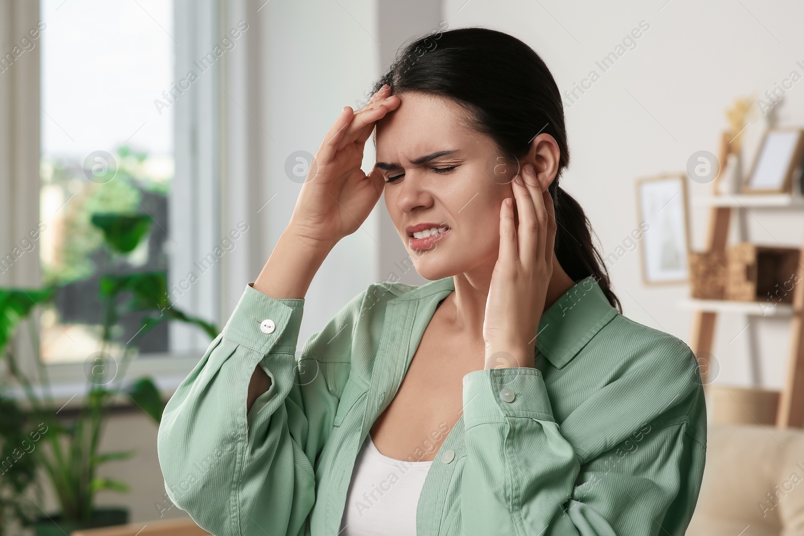 Photo of Young woman suffering from ear pain at home