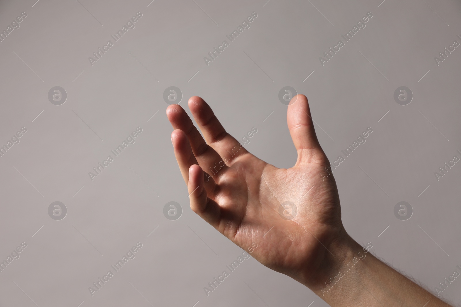 Photo of Man holding something in hand on grey background, closeup. Space for text