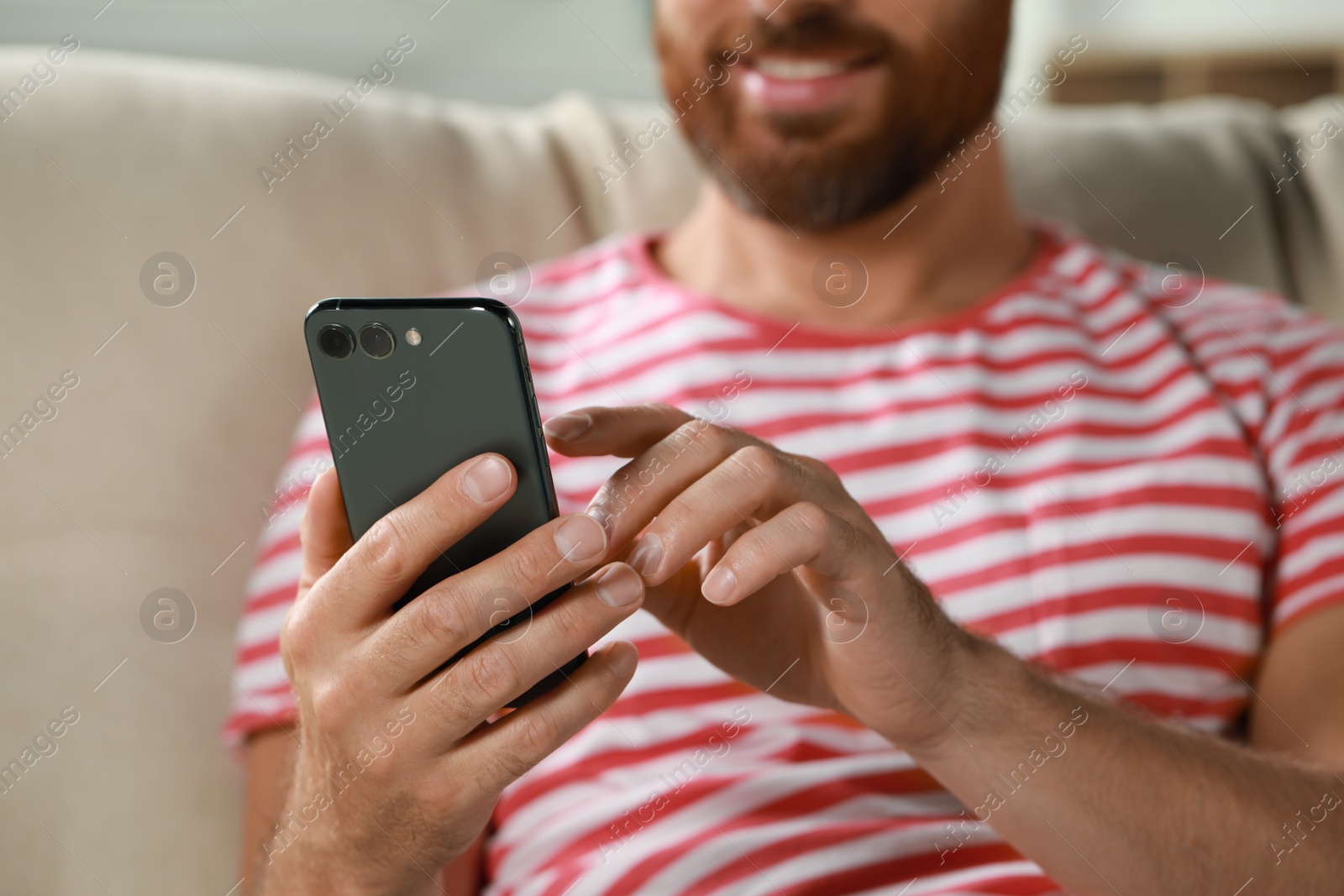 Photo of Man using smartphone at home, closeup view