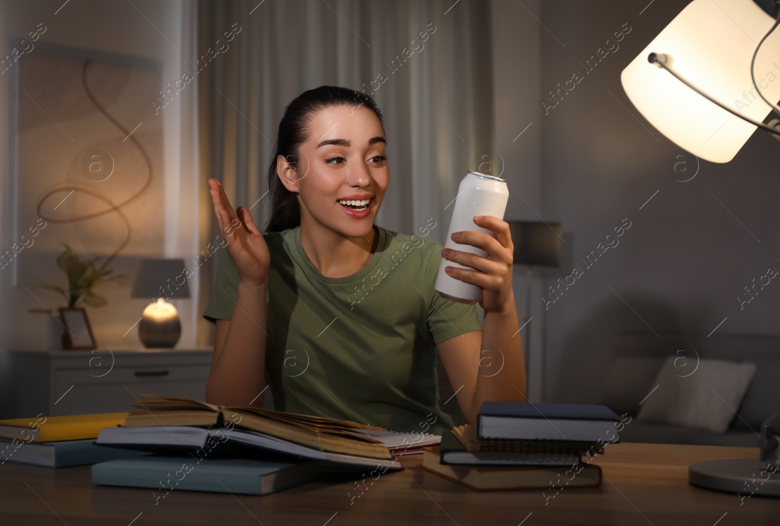 Photo of Young woman with energy drink studying at home