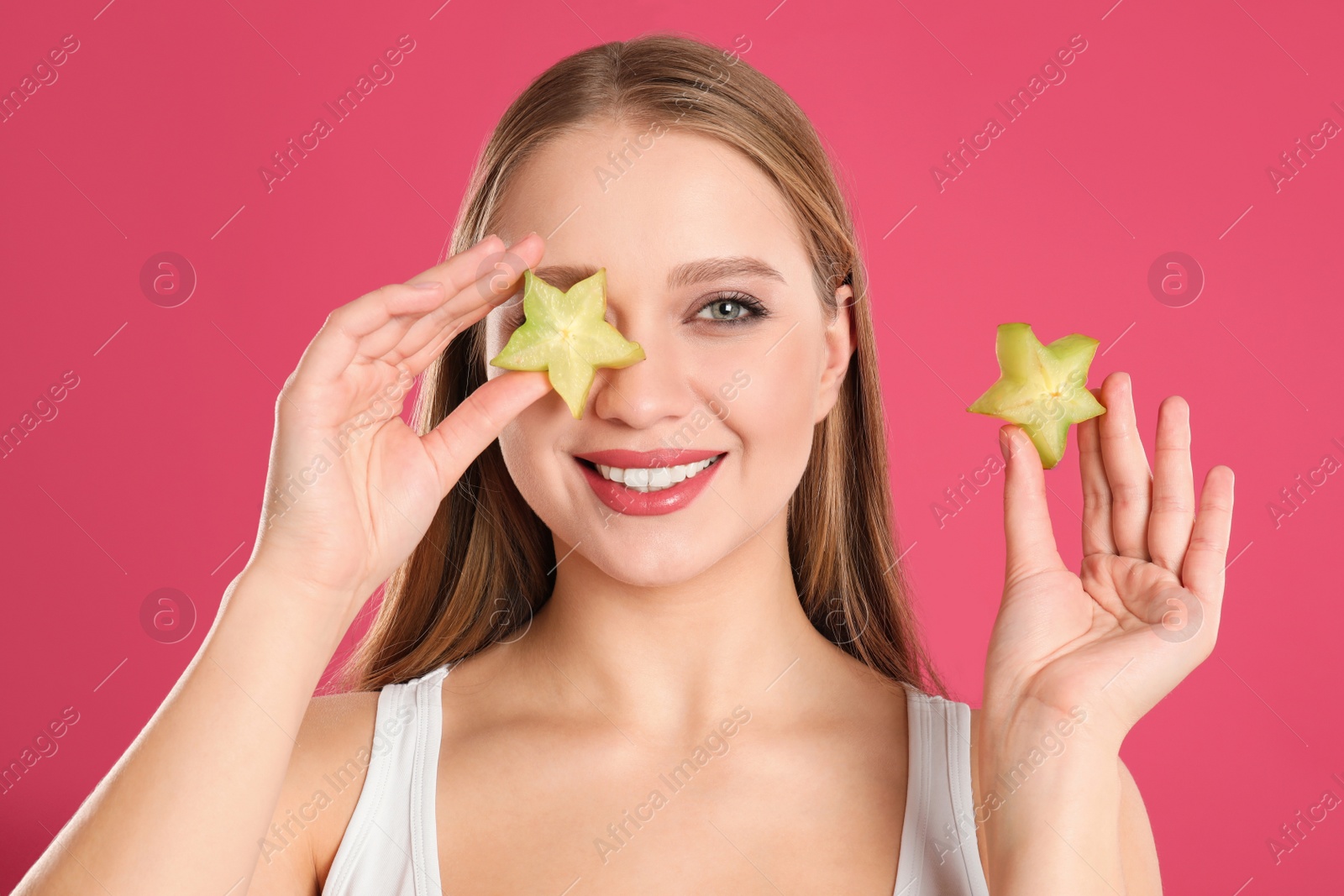 Photo of Young woman with cut carambola on pink background. Vitamin rich food