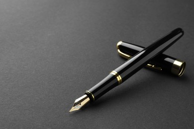 Photo of Stylish fountain pen with cap on black background. Space for text