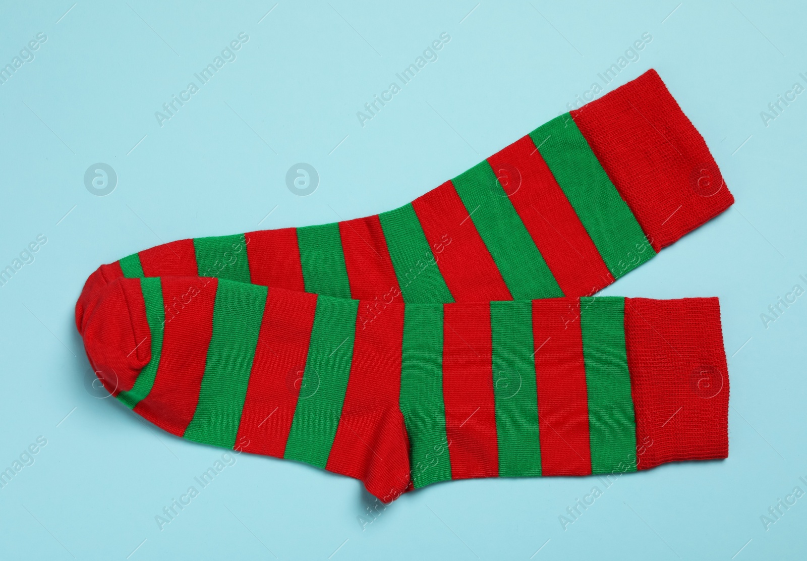 Photo of Pair of new striped socks on light blue background, flat lay
