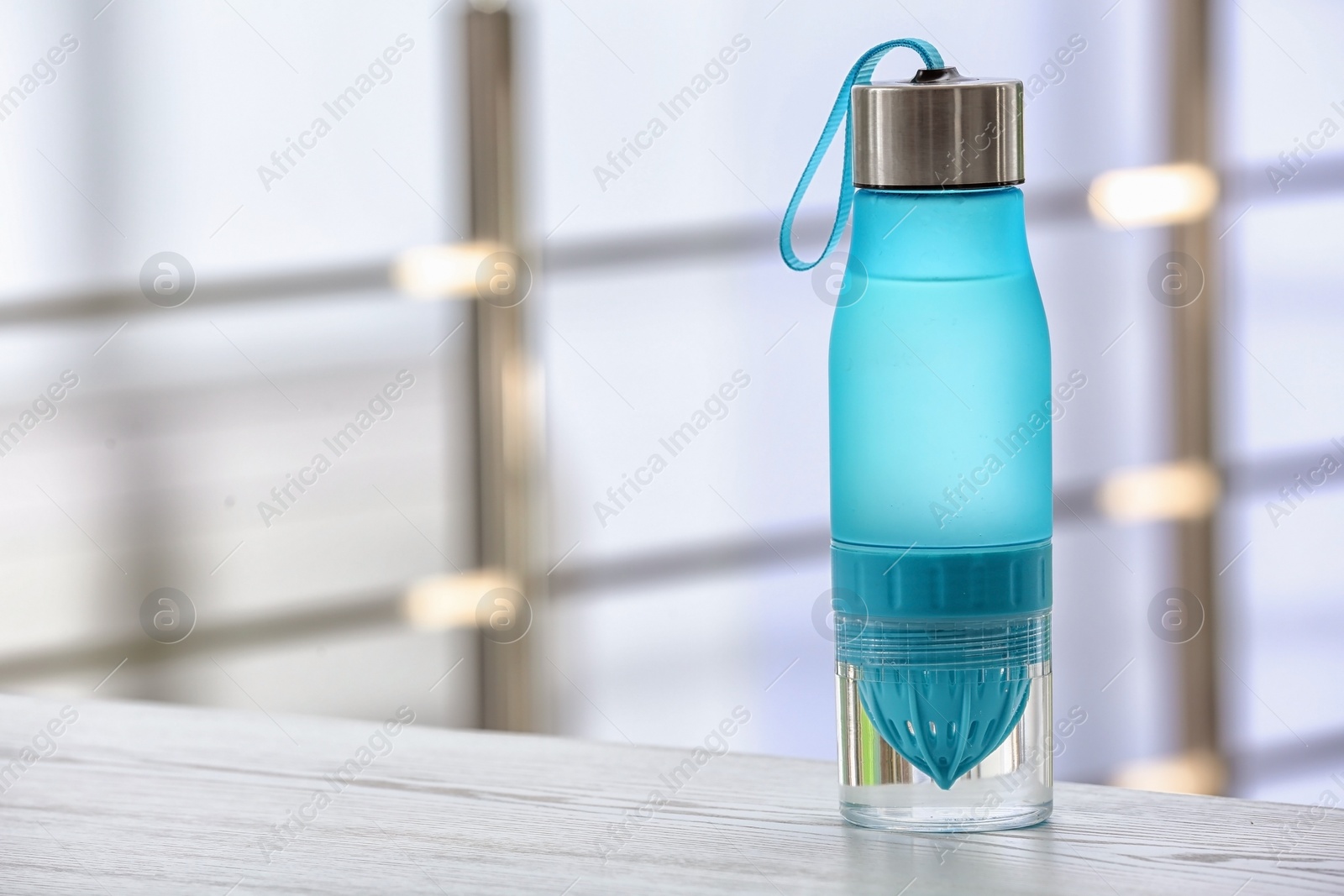 Photo of Sports water bottle on table against blurred background. Space for text