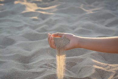 Girl pouring sand from hand outdoors, closeup. Fleeting time concept