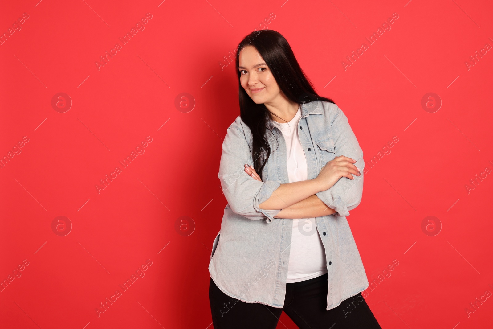 Photo of Beautiful overweight woman with charming smile on red background. Space for text