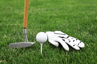 Photo of Golf club with ball, tee and glove on green grass