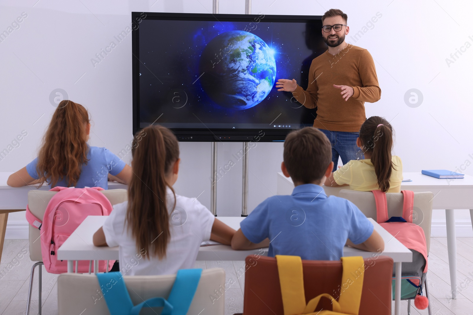 Photo of Teacher near interactive board in classroom during lesson