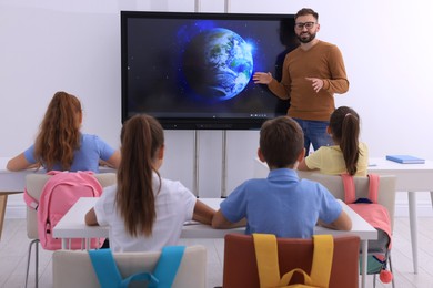Photo of Teacher near interactive board in classroom during lesson