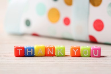 Photo of Phrase Thank You made of colorful cubes on light wooden table