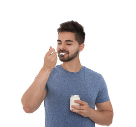 Happy young man eating tasty yogurt on white background