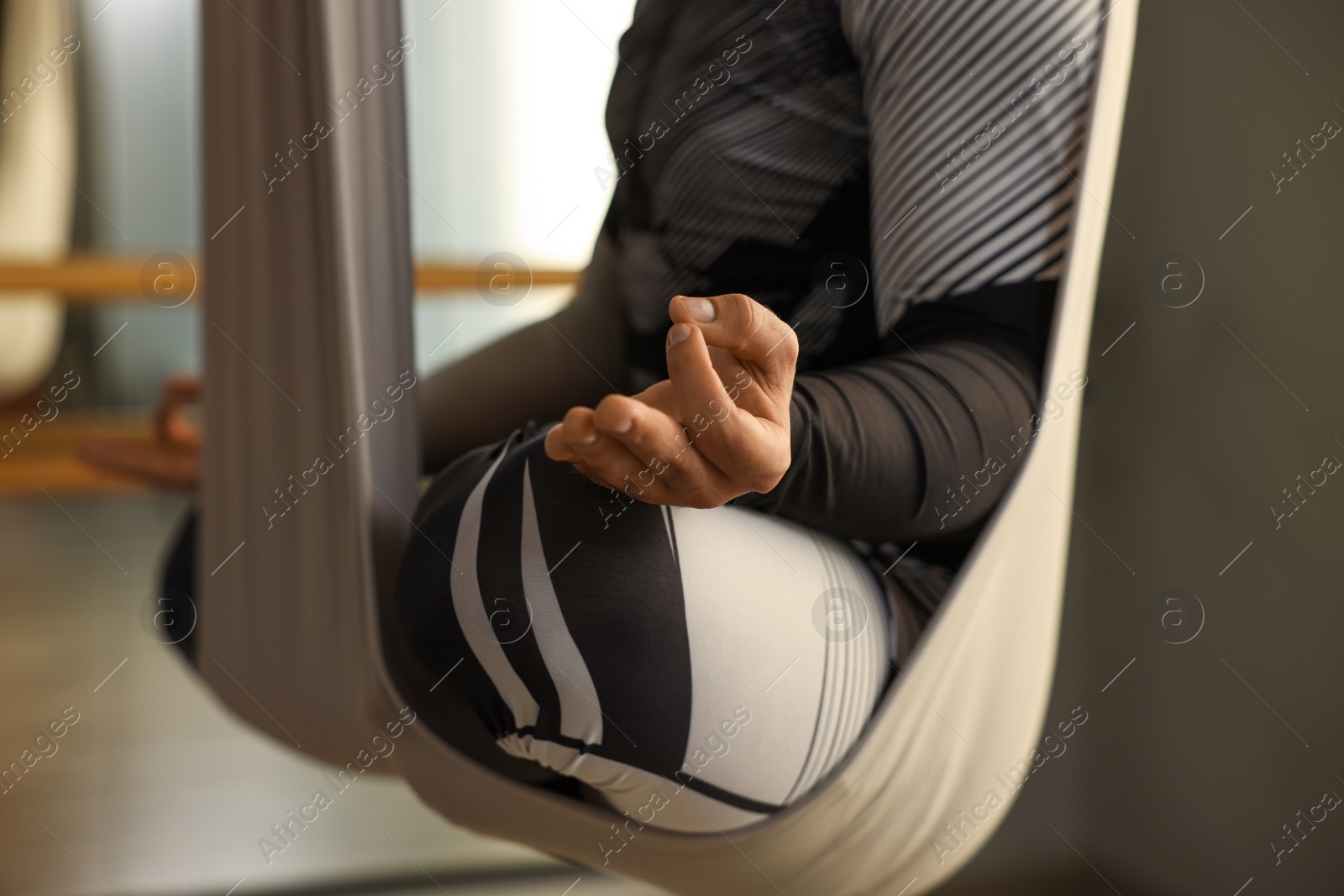 Photo of Man meditating in fly yoga hammock indoors, closeup