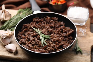 Photo of Fried ground meat in frying pan and products on table, closeup