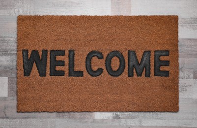 Photo of New clean mat with word WELCOME on floor, top view