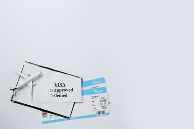 Photo of Passport, toy plane and tickets on white background, top view. Visa receiving